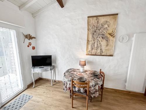 a room with a table and a television and a table and chairs at Douceur de vivre, calme et jardin Appartement 3 in Médis