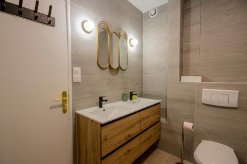 La salle de bains est pourvue d'un lavabo, de toilettes et de miroirs. dans l'établissement Appartement cosy aux coeur de Paris - 10 pers, à Paris
