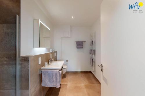 a white bathroom with a sink and a toilet at Haus Seeblick Ferienwohnung Nordseekieker in Wangerooge