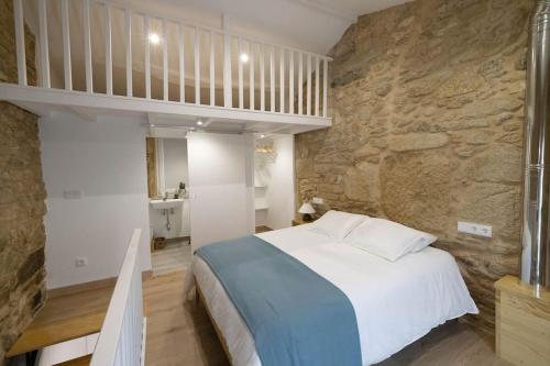 a bedroom with a large bed and a stone wall at Casa Soledá e Pepa in Outes