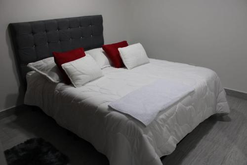 a large bed with red and white pillows on it at Hospedaje BOGOTA cerca al aeropuerto in Bogotá