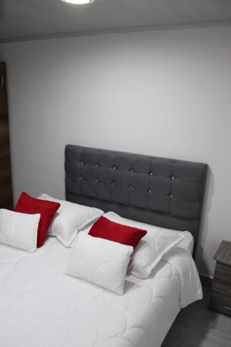 a large white bed with red and white pillows at Hospedaje BOGOTA cerca al aeropuerto in Bogotá