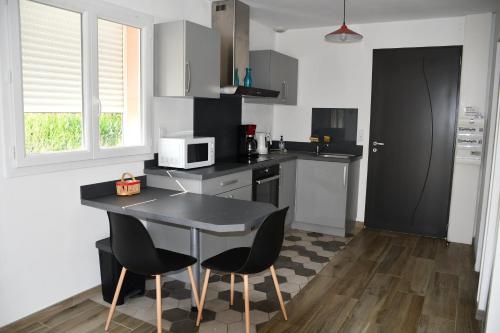 une cuisine avec une table et des chaises et un micro-ondes dans l'établissement Joli studio avec piscine, à Ger