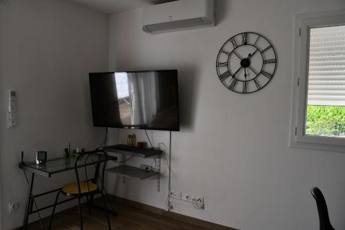 Cette chambre dispose d'une télévision et d'une horloge murale. dans l'établissement Joli studio avec piscine, à Ger
