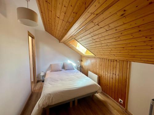 un grand lit dans une chambre avec un plafond en bois dans l'établissement Jolie maison entièrement rénovée à la montagne, à Villar-Saint-Pancrace