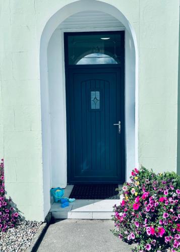 a black door in a white building with flowers at BlueSeaView Apartment with fabulous sea views in Newcastle