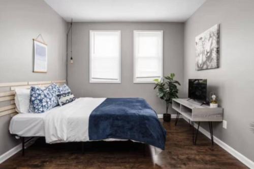 a bedroom with a bed and a desk and windows at Cozy 1BR Getaway - BBQ - Backyard - Pet - Friendly in Indianapolis