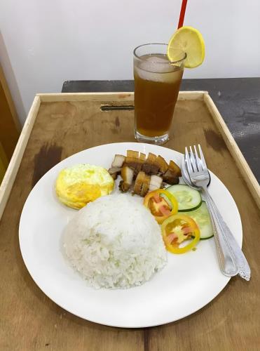 une assiette de nourriture avec du riz et une boisson sur un plateau dans l'établissement Vhora Resort, à Magdiwang