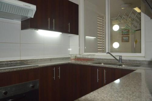 a kitchen with brown cabinets and a sink and a mirror at Depto frente al mar con wifi Se permiten mascotas Mac06 in La Serena