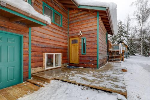 a log cabin with a green door in the snow at Ideally Located Fairbanks Vacation Rental! in Fairbanks
