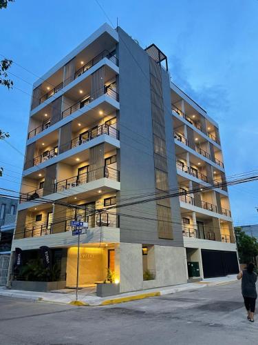 an apartment building with a woman walking past it at Levitat Hunah in Playa del Carmen