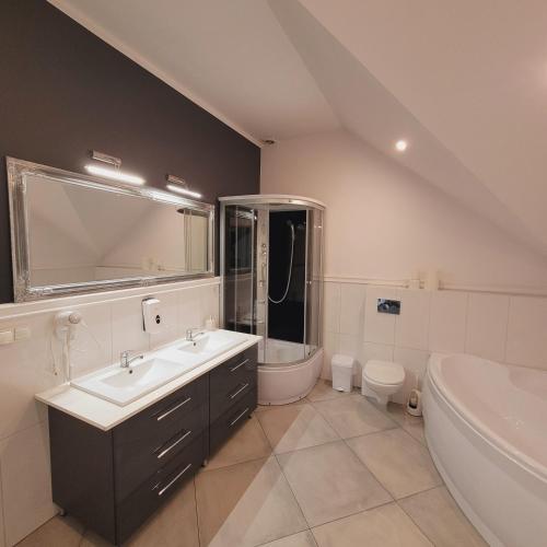 a bathroom with a sink and a tub and a toilet at Ostoja Apartament in Morąg