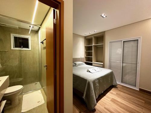 a bedroom with a bed and a bathroom with a shower at Aptos perfeito para suas férias, surpreenda a todos in Ubatuba