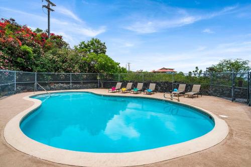 a swimming pool with chairs and a fence at Kona Mansions#304 in Kailua-Kona