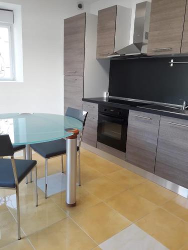 une cuisine avec une table et des chaises en verre dans l'établissement La maison du parc, à Vervant