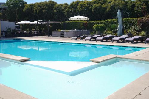 a large blue swimming pool with chairs and umbrellas at Hotel La Rocca in Nogarole Rocca