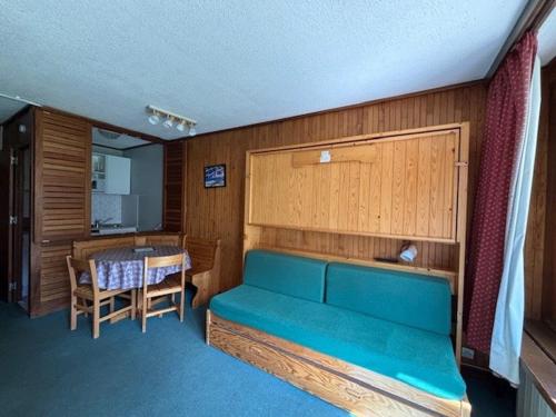 une chambre avec un canapé bleu et une table dans l'établissement Studio 25m² à 20M des pistes, balcon sud/ouest, 4 pers., TV - FR-1-449-144, à Tignes