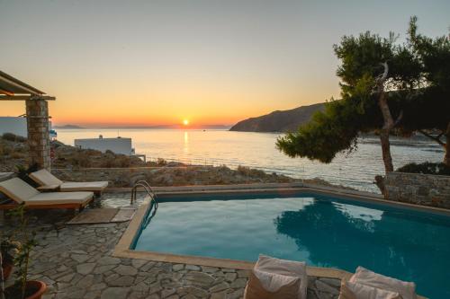 a swimming pool with a view of the ocean at sunset at Yperia Hotel in Aegiali