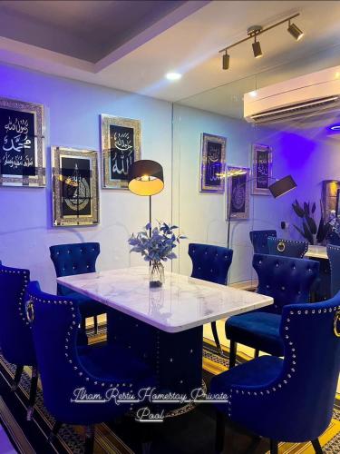 a dining room with a table and blue chairs at Ilham Restu Homestay Private Pool MSLIM ONLY in Port Dickson