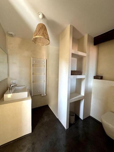 La salle de bains est pourvue d'un lavabo, de toilettes et d'une lumière. dans l'établissement Charming air-conditioned house with garden & view, à Olmeto