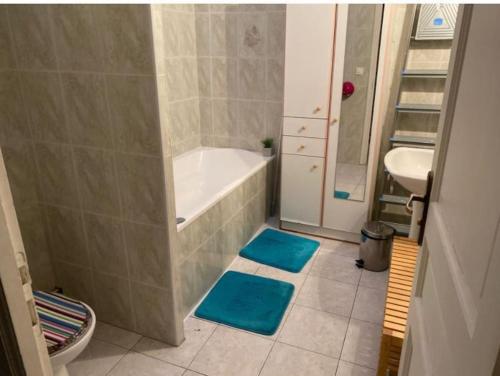 La salle de bains est pourvue d'une baignoire, d'un lavabo et de tapis bleus. dans l'établissement Plein Cœur de Sanary sur Mer, à Sanary-sur-Mer