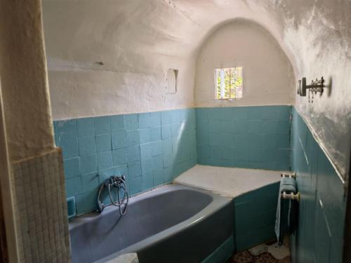 La salle de bains est pourvue d'une baignoire et de carrelage bleu. dans l'établissement Maison dans l'arrière pays niçois entre mer et montagne, à Tourrette-Levens
