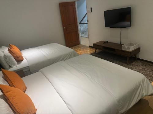 two beds in a hotel room with a television at Jambul Villa 3-storey corner House 6Bed5Bathroom in Bayan Lepas
