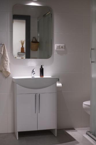 a white bathroom with a sink and a mirror at NOI Resort SPA - woda i las in Tęgoborze
