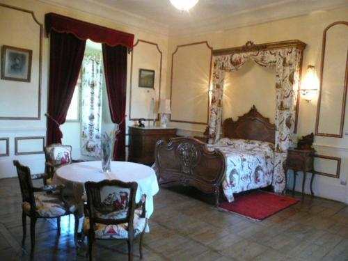 a bedroom with a bed and a table and chairs at Château De Saint-Maixant in Saint-Maixant