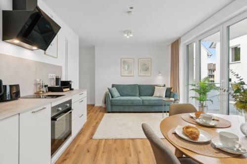 a kitchen and living room with a table and a couch at Stylisches Apartment mit Balkon & kostenlosem Parkplatz Beste Lage in Bielefeld in Bielefeld