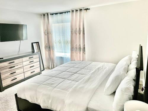 a white bedroom with a large bed and a television at Spacious 4-bedroom house,6beds with office space in Charlotte