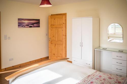 a bedroom with a bed and a wooden door at Atlantic Sunset in Aughrus More