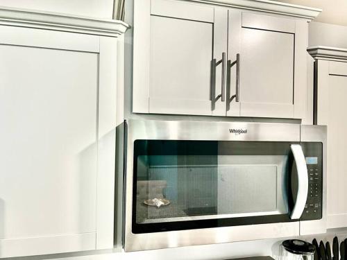 a microwave oven in a kitchen with white cabinets at Spacious 4-bedroom house,6beds with office space in Charlotte