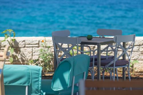a table and chairs sitting next to the water at Callisto Seaside Homes & Suites in Marathopolis