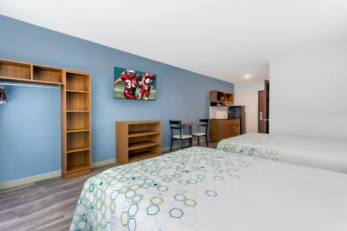 a bedroom with two beds and a blue wall at HomeTowne Studios by Red Roof Tampa - Airport in Tampa