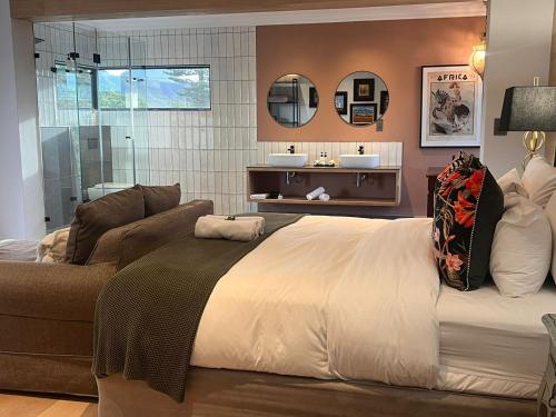 a bedroom with a bed and a couch and mirror at The Whale's Tale Guesthouse in Hermanus