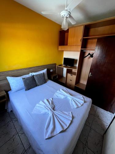 a bedroom with a white bed with a yellow wall at Pousada Morada Dusanjos in Caraguatatuba