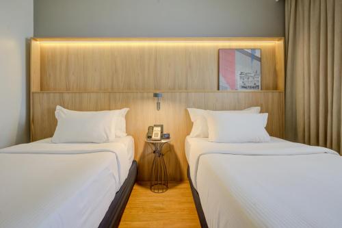 two beds in a hotel room with a phone between them at Hampton by Hilton Guarulhos Airport in Guarulhos