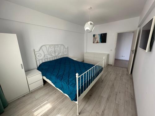 a white bedroom with a blue bed and a chair at Apartament Anne Marie - Ibo Residence in Mamaia Nord