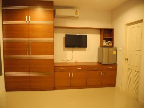 a room with wooden cabinets and a tv in a room at Green House Phuket in Ban Pa Khlok