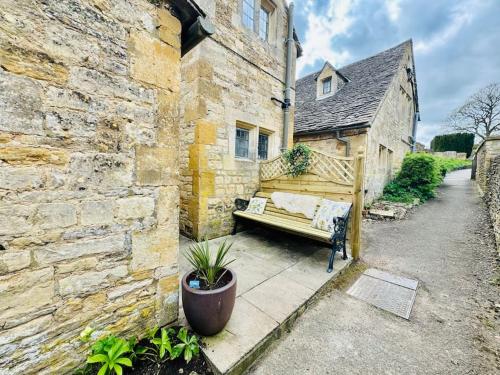 a bench sitting in the courtyard of a building at Fordview Cottage is full of Cotwolds Charm in Upper Slaughter