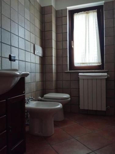 a bathroom with a toilet and a sink and a window at Appartamento Mainarde in Capracotta