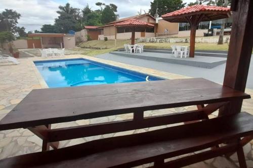 a wooden bench sitting in front of a swimming pool at Chácara Harmonia Pouso Alegre in Pouso Alegre
