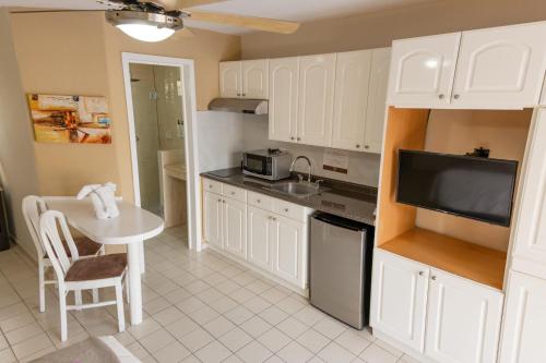 a kitchen with white cabinets and a table and a tv at Hotel Santa Fe Los Cabos by Villa Group in Cabo San Lucas
