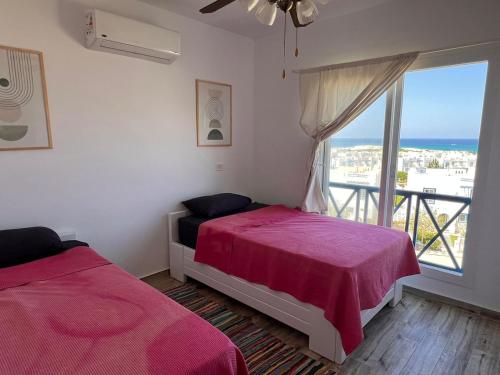 a bedroom with two beds and a large window at Spacious 3BR Apartment w Rooftop Terrace Jacuzzi in Ras Elhekma