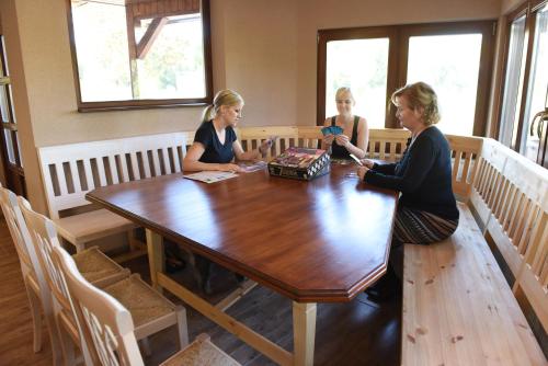 three women sitting at a table in a room at aQuarium Panzió in Abádszalók