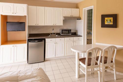a kitchen with white cabinets and a table and chairs at Hotel Santa Fe Los Cabos by Villa Group in Cabo San Lucas