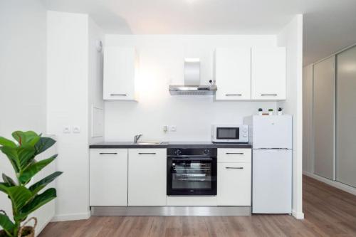 une cuisine avec des armoires blanches et un appareil noir dans l'établissement Cosy F2 à Bondy, à Bondy