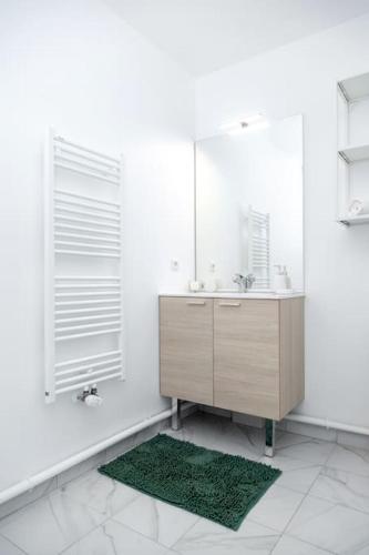 une salle de bain blanche avec un lavabo et un miroir dans l'établissement Cosy F2 à Bondy, à Bondy