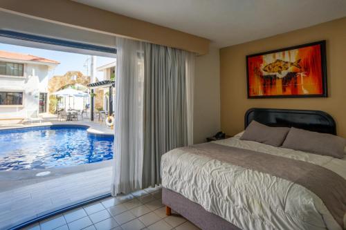 a bedroom with a bed and a large window with a pool at Hotel Santa Fe Los Cabos by Villa Group in Cabo San Lucas